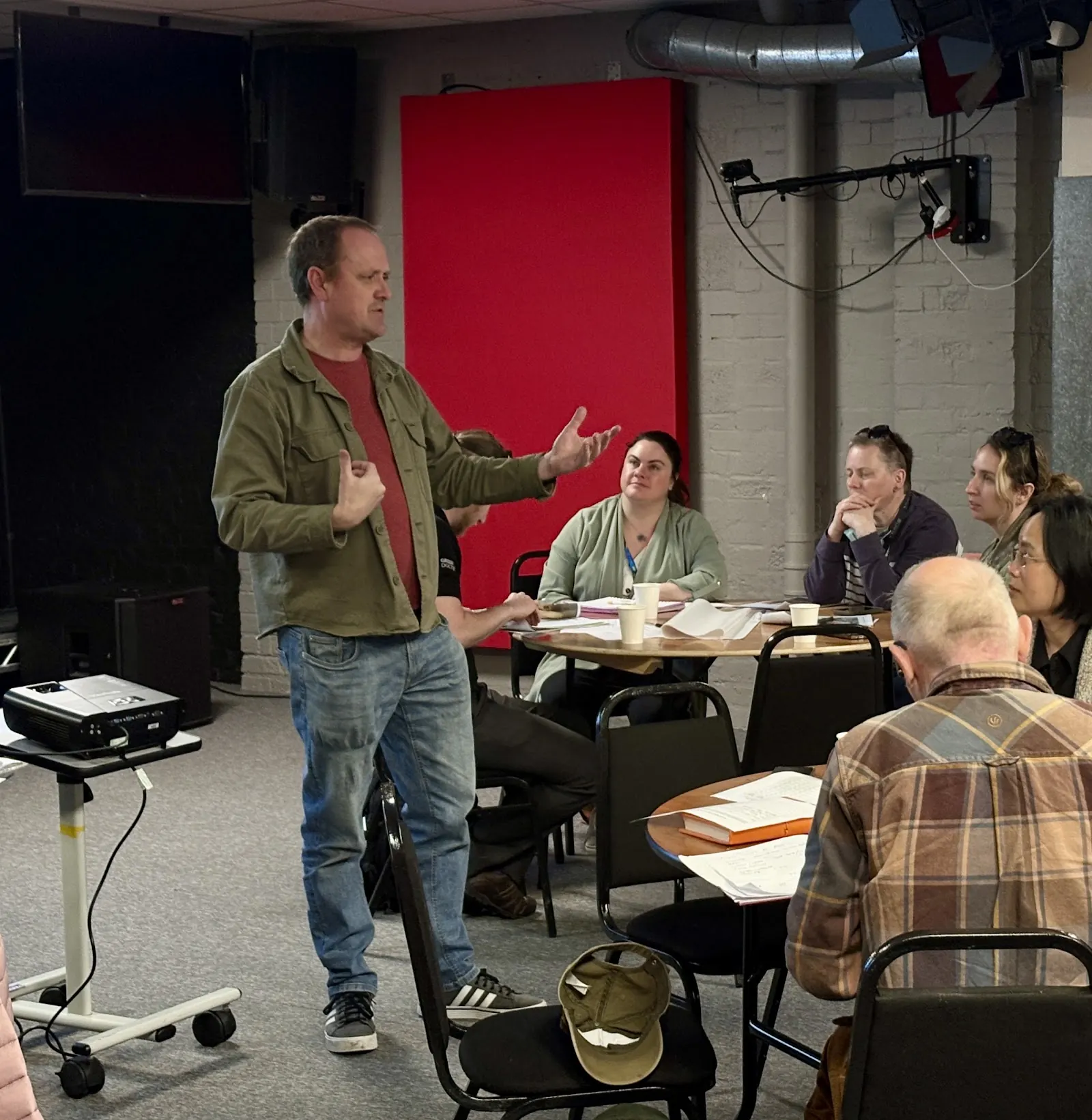 A Community Connector speaking to partners sitting at round tables